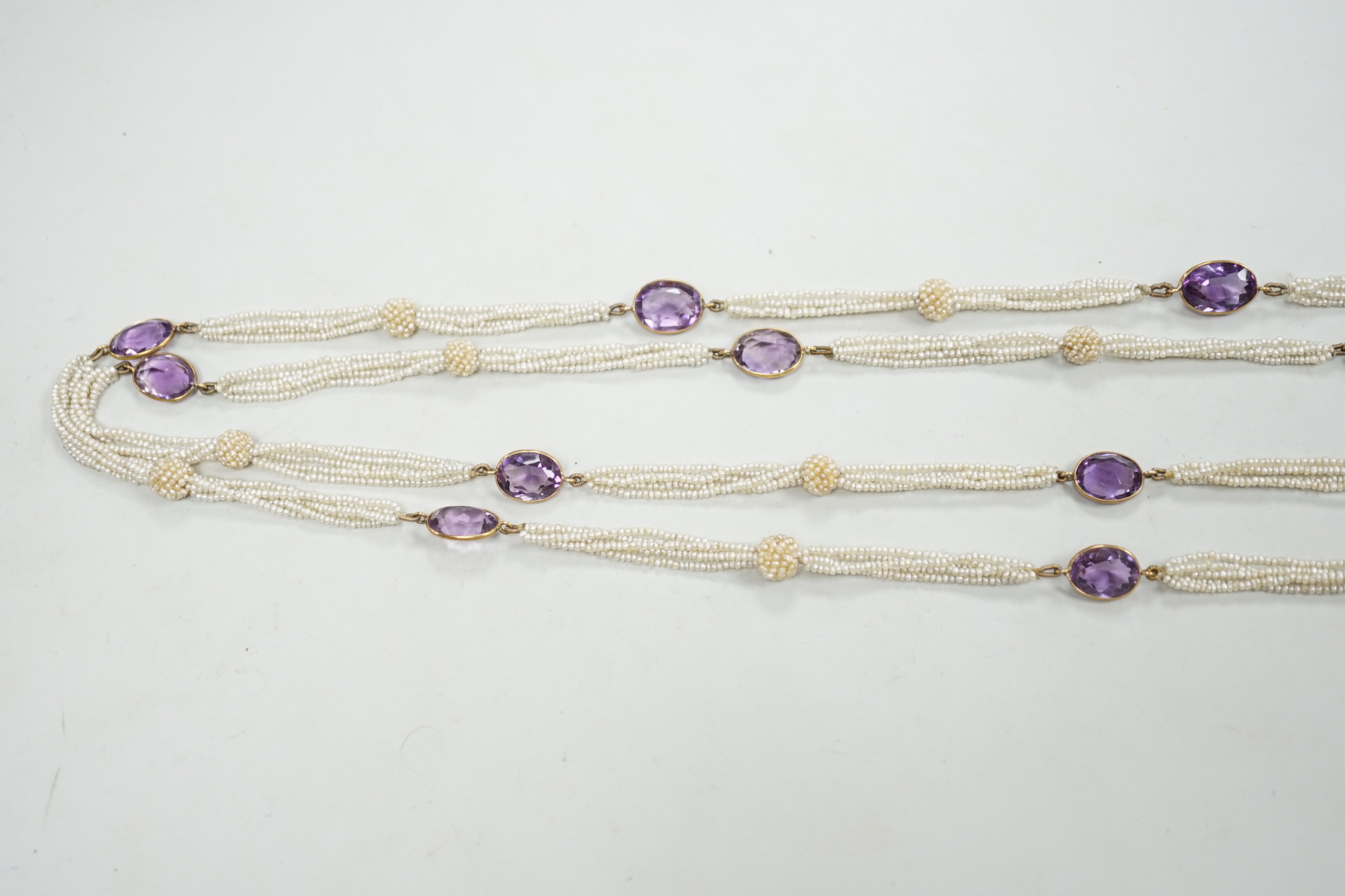 A 19th century Indian multi strand seed pearl and oval cut amethyst set long necklace, with gem set tassel terminals, 170cm.